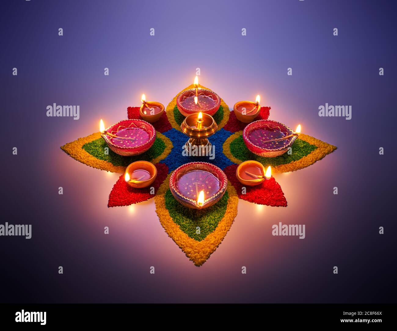 Happy Diwali, lampade diya accese su rangoli colorati Foto Stock