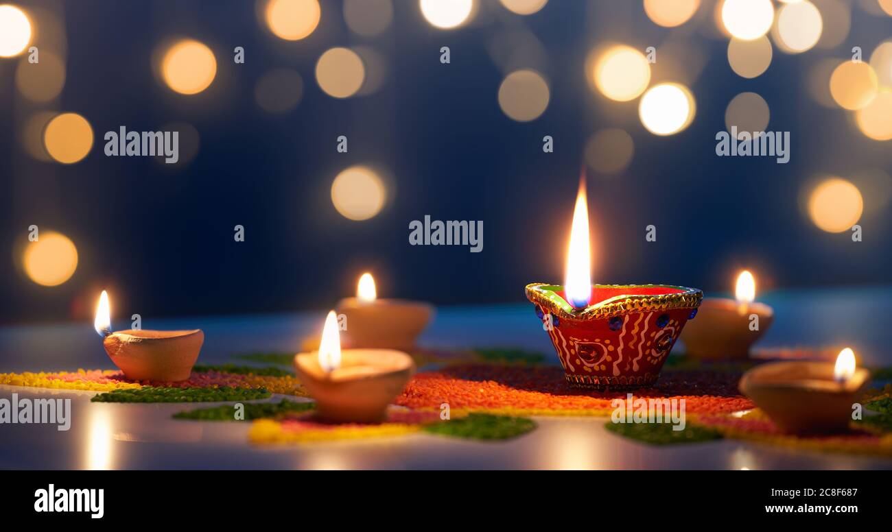 Happy Diwali, lampade Diya illuminate su rangoli colorati con sfondo bokeh chiaro Foto Stock