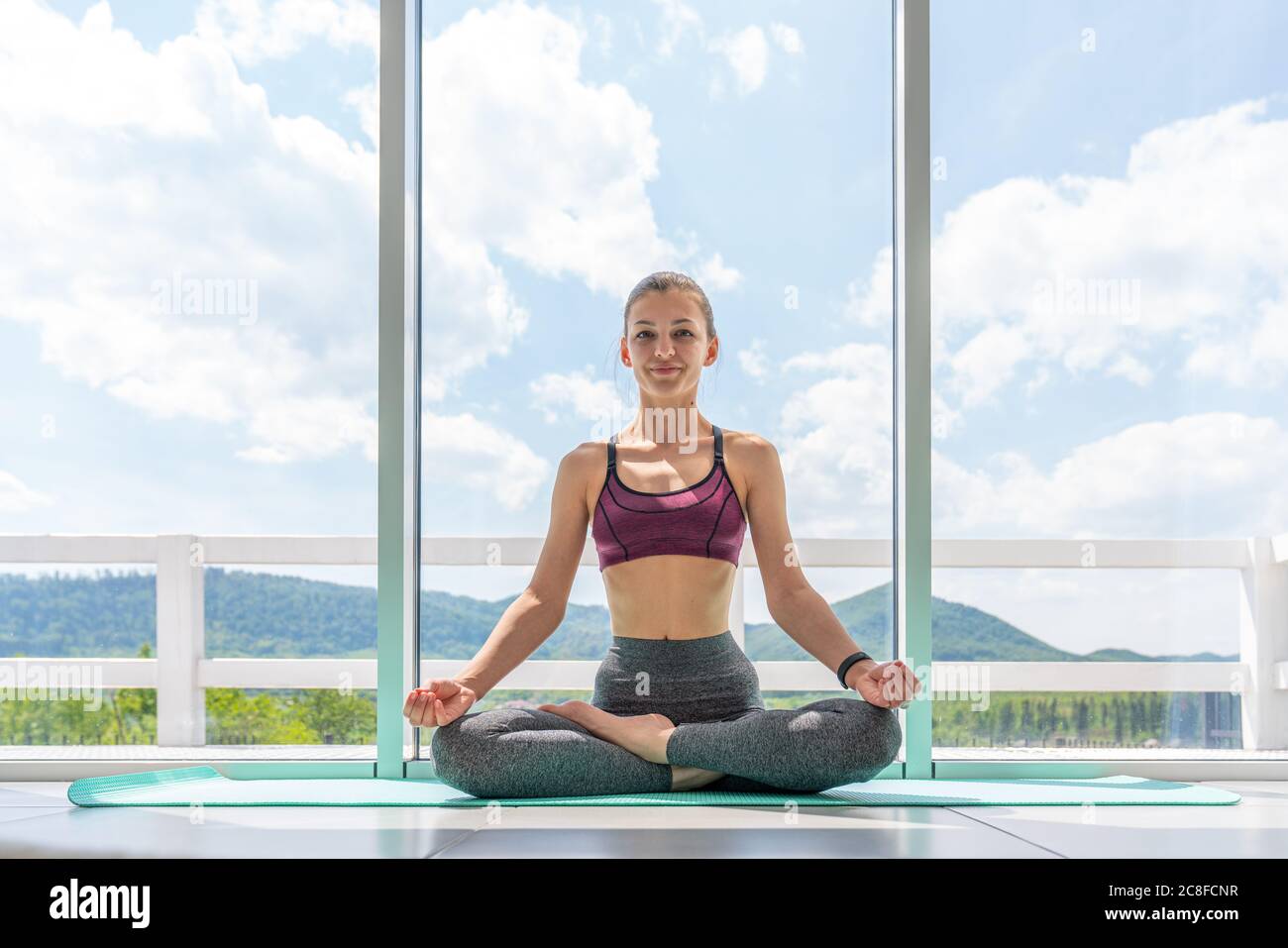 Yoga a casa. Mantenere la calma. Bella giovane donna seduta su lotus posizione sul pavimento Foto Stock