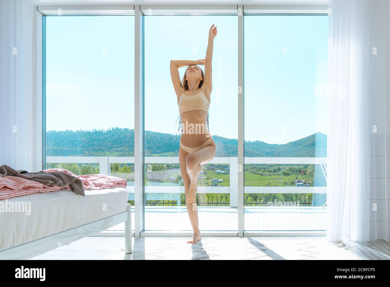 Ritratto di donna sportiva in reggiseno bianco o intimo vicino alla finestra. Relax vicino alla finestra Foto Stock