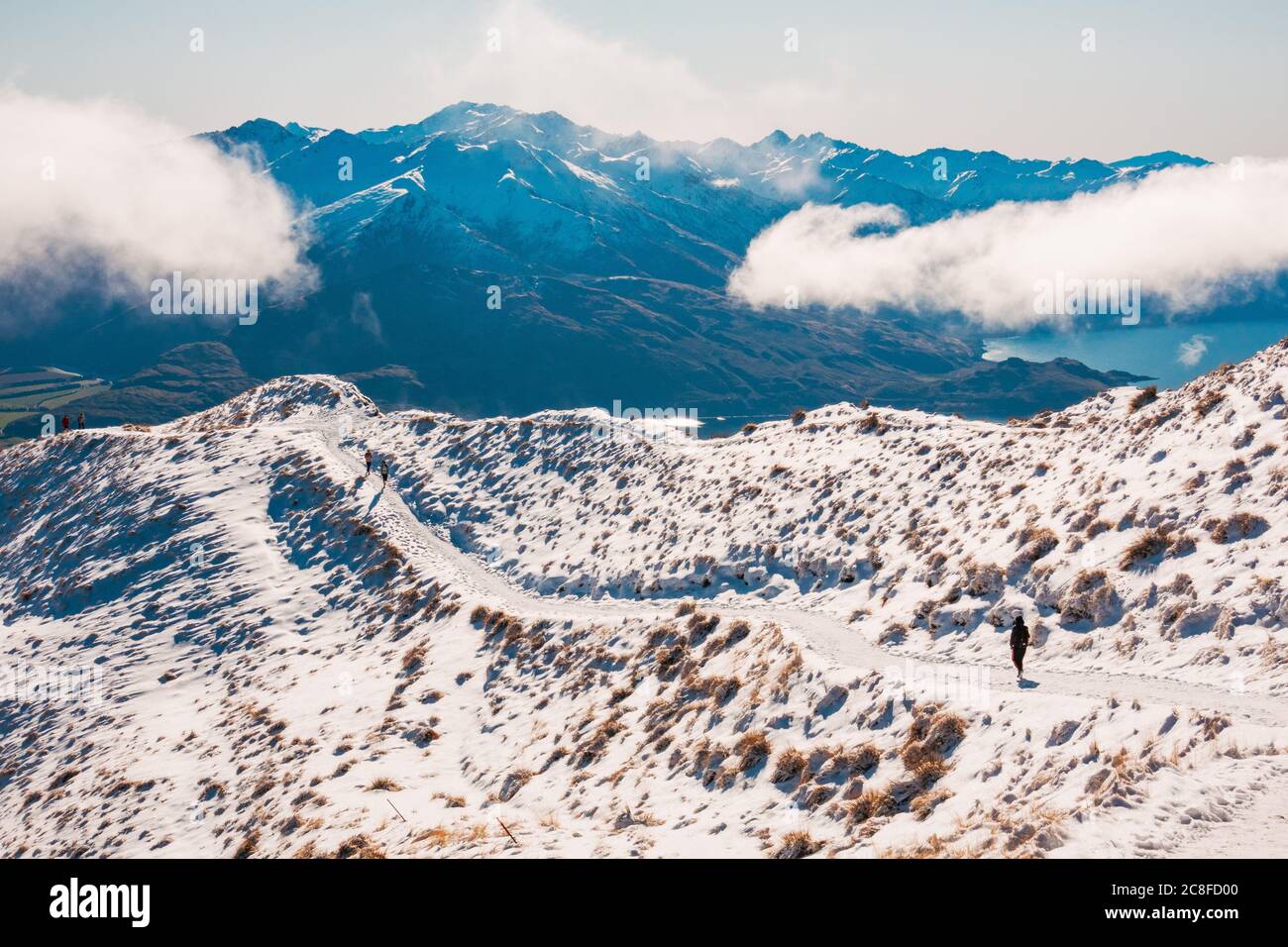 Un turista cammina lungo la pista innevata lungo il crinale di Roys Peak, Wanaka, Nuova Zelanda Foto Stock