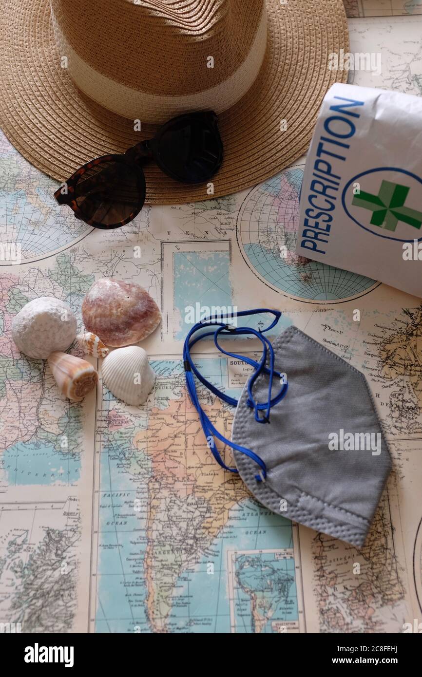 Maschera di Covid, cose di viaggio di vacanza, meds sulla mappa del mondo con spazio di copia Foto Stock