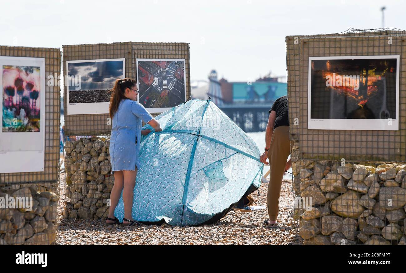 Brighton UK 24 luglio 2020 - i visitatori godono di una calda giornata di sole sulla spiaggia di Brighton con previsioni di temperature per raggiungere i 25 gradi in alcune parti del Sud-Est di oggi: Credit Simon Dack / Alamy Live News Foto Stock