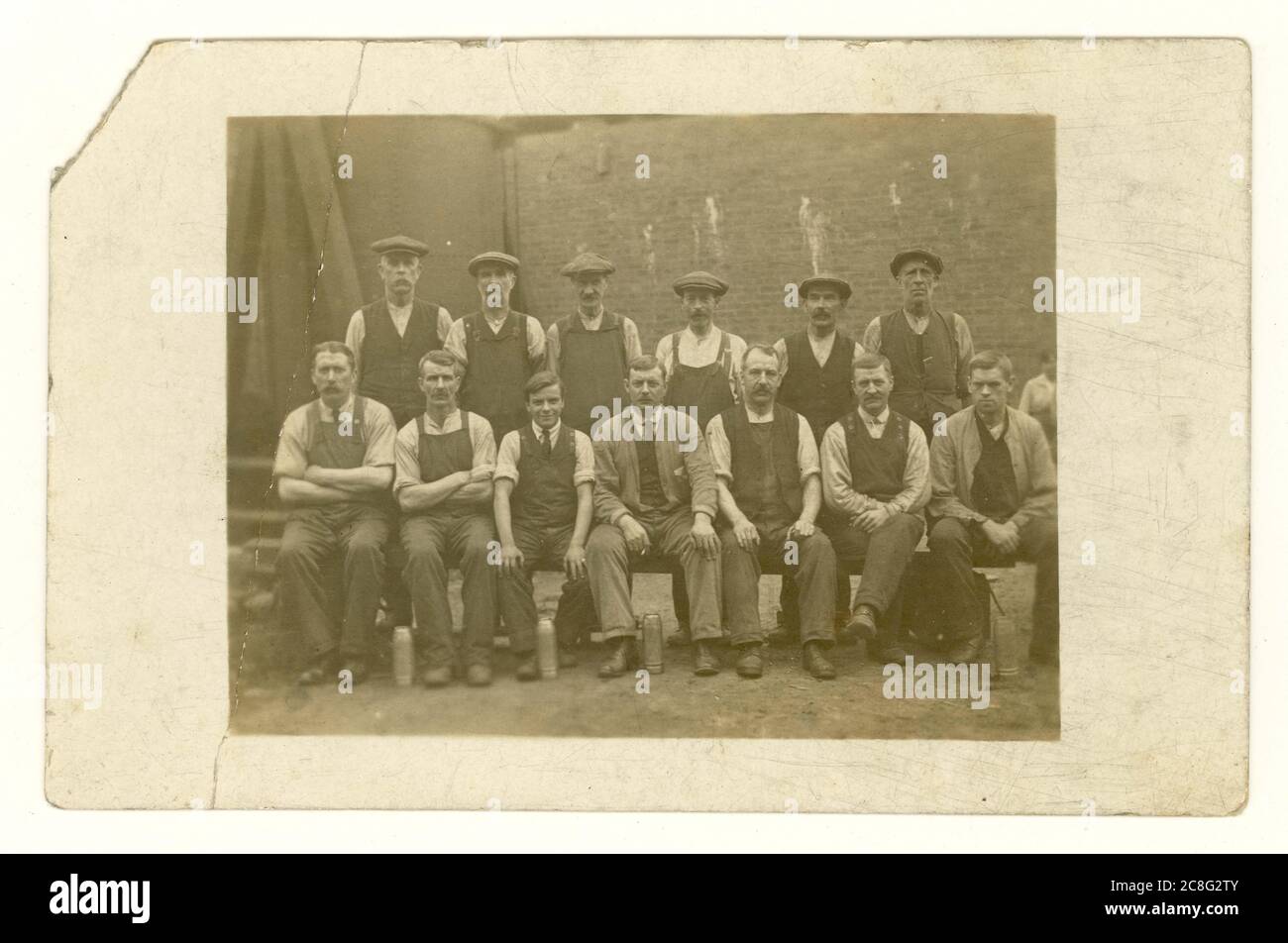 Cartolina degli inizi del 1900 di uomini in classe operaia all'esterno in cortile con tappi piatti, con matracci, circa 1907, Regno Unito Foto Stock