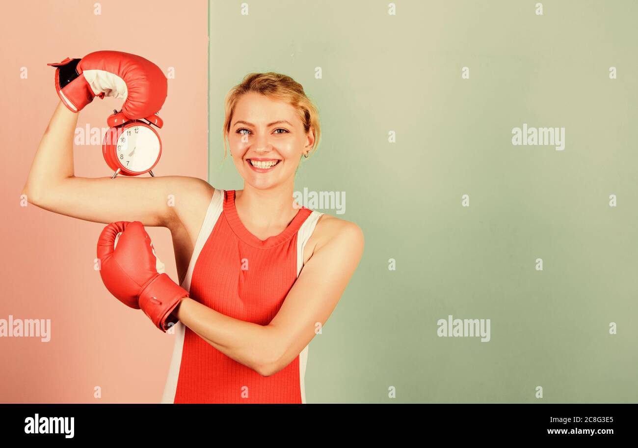 Puntualità ed efficienza personale. Ragazza boxer tenere sveglia. Energia del mattino. Stabilire l'ora. Copiare spazio. Tempo di lotta. Tempo per il successo. Vincere il giorno. Felice donna pugilato guanti. Foto Stock