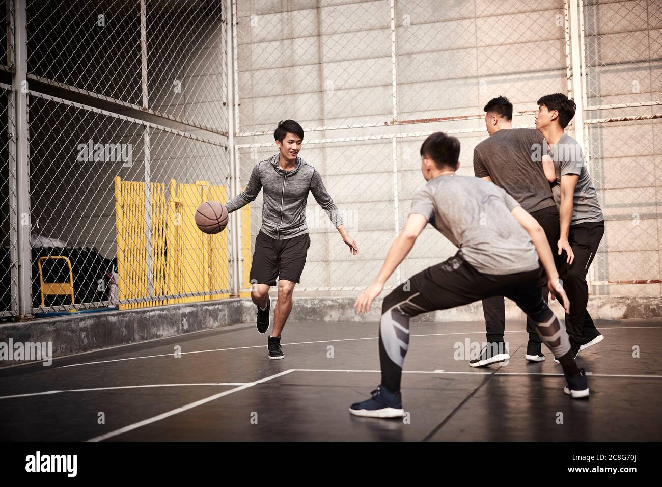 giovani uomini adulti asiatici che giocano a basket sul campo all'aperto Foto Stock