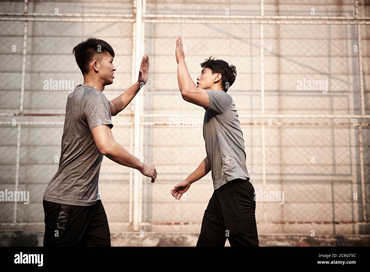 due giovani atleti asiatici che danno un successo hive-five festeggiando Foto Stock