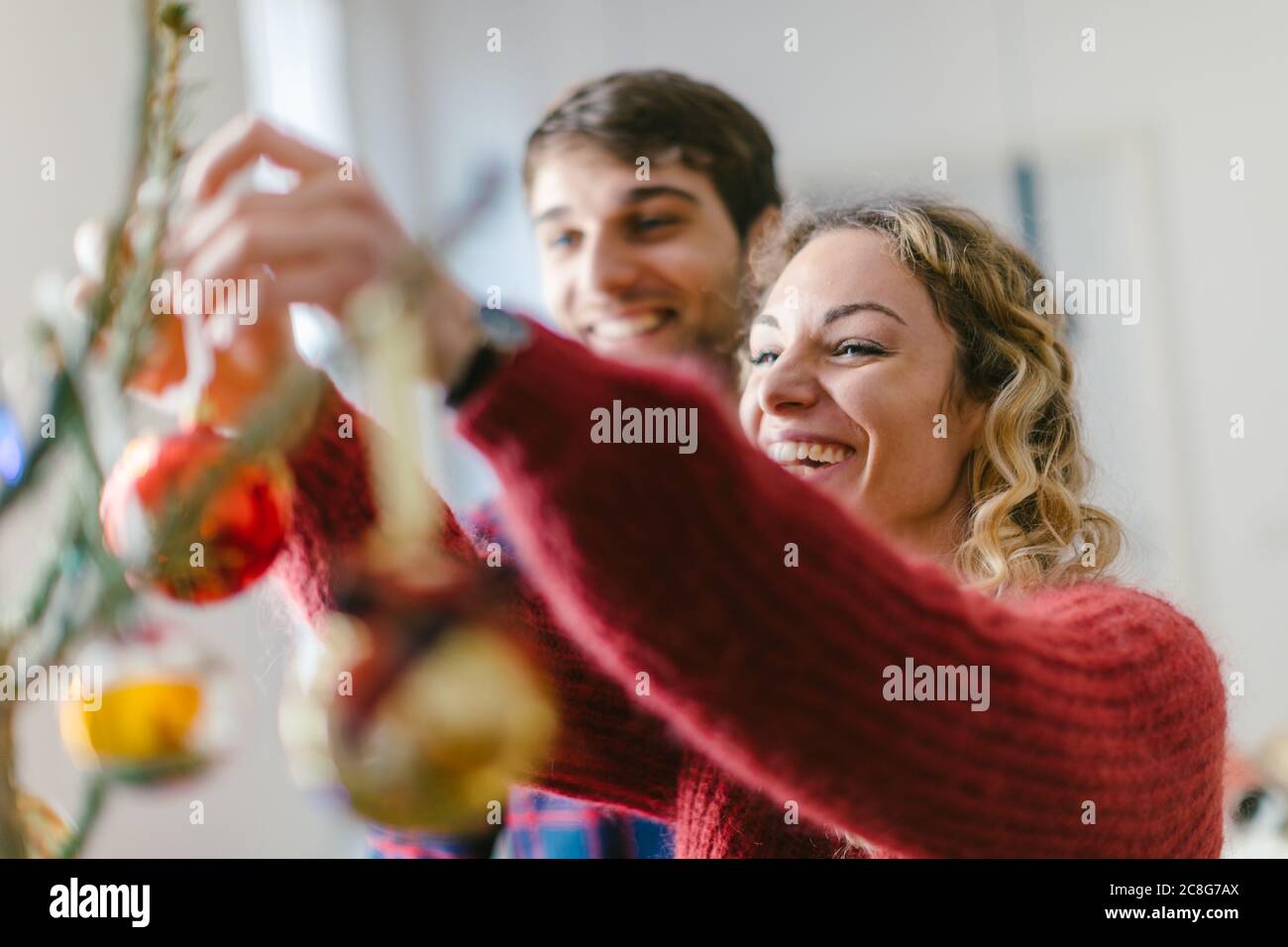 Giovane decorare albero di Natale a casa Foto Stock