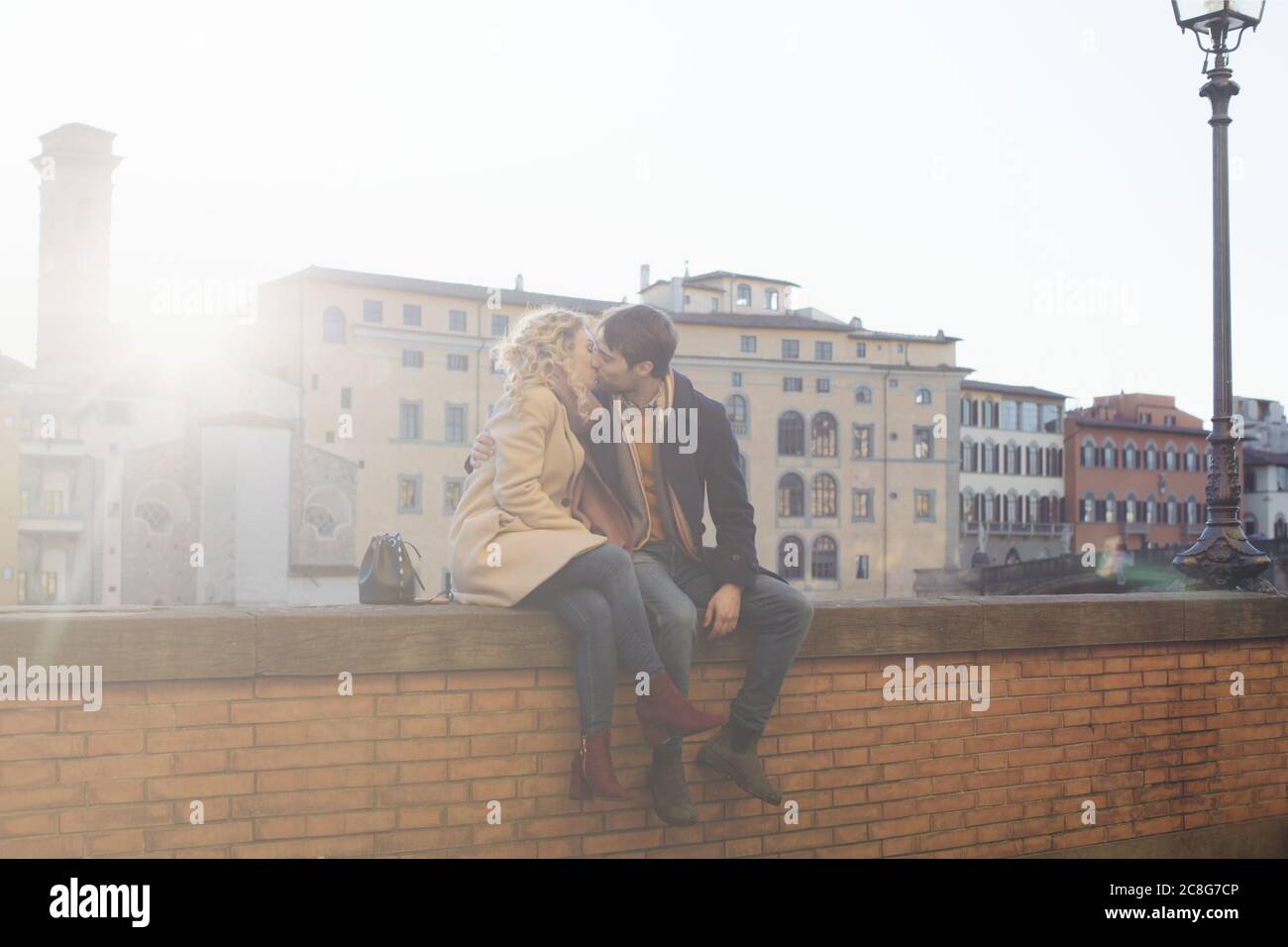 Giovane baciare sulla parete di mattoni, Firenze, Toscana, Italia Foto Stock