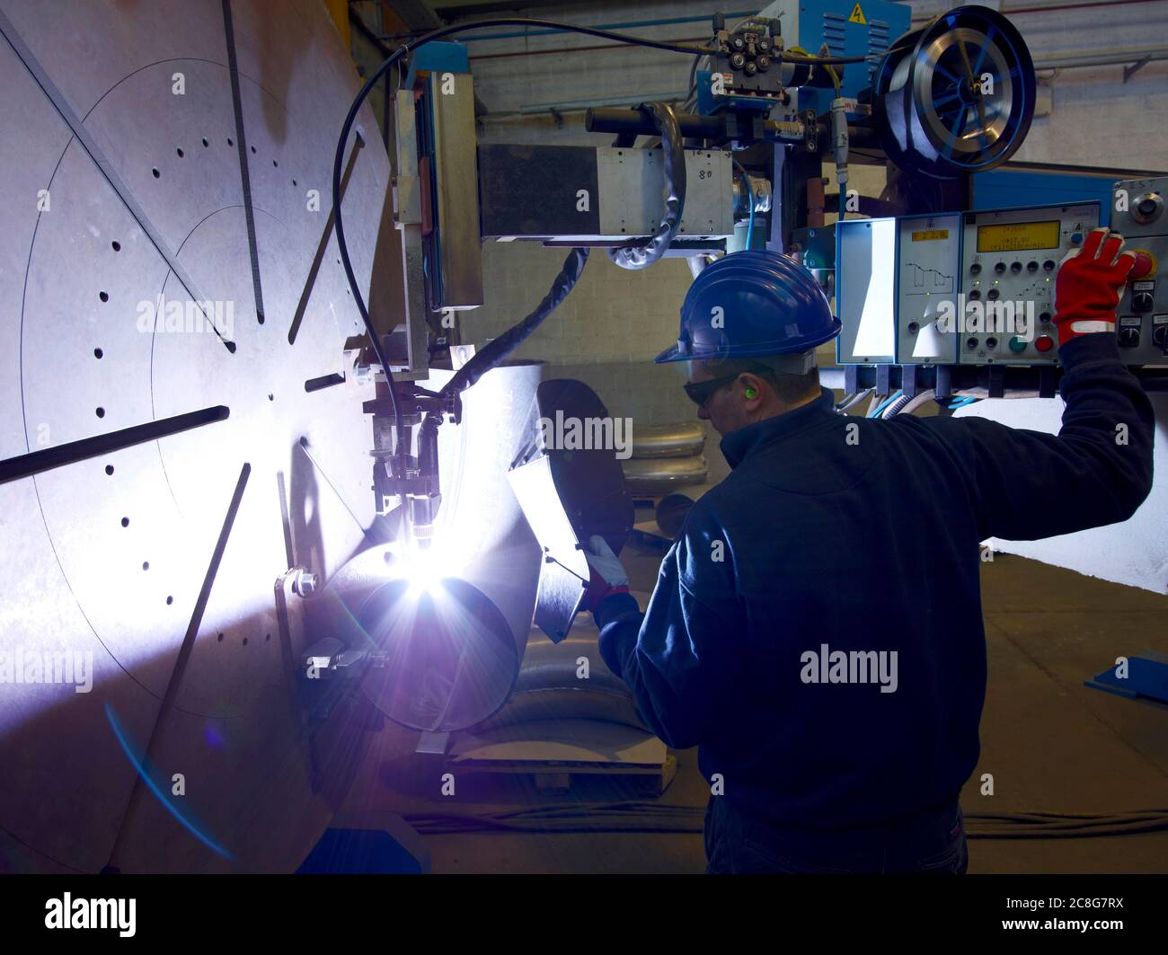 Uomo che indossa una maschera di saldatura che lavora in una fabbrica di acciaio. Foto Stock