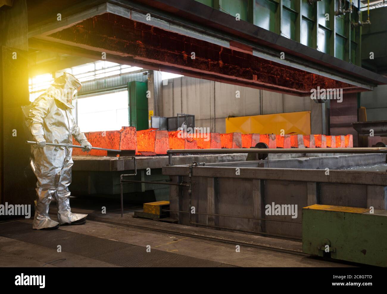 Uomo che indossa una tuta termica argentata che lavora in una fabbrica di acciaio. Foto Stock