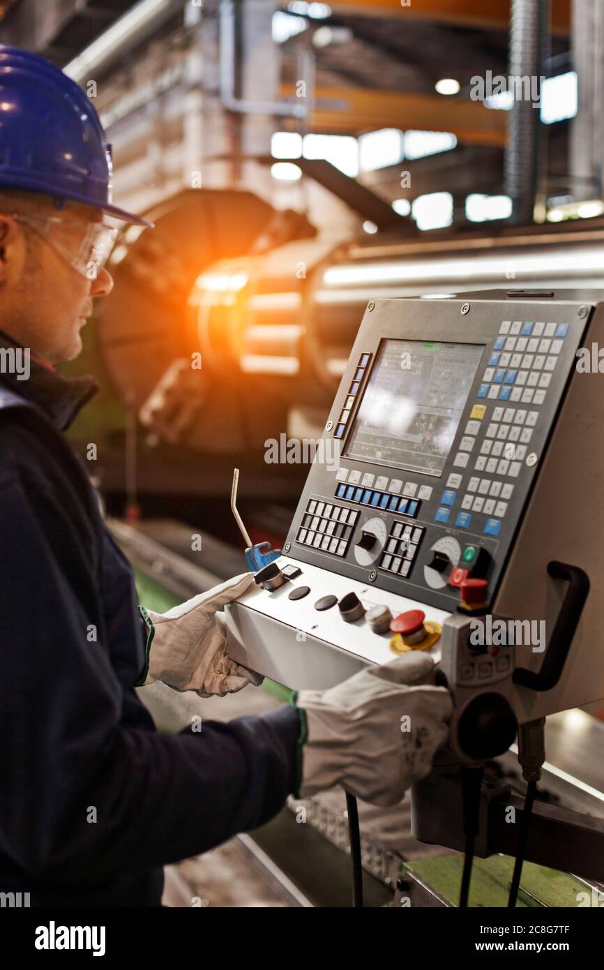 Uomo che lavora in una fabbrica d'acciaio, che lavora su una macchina computerizzata. Foto Stock