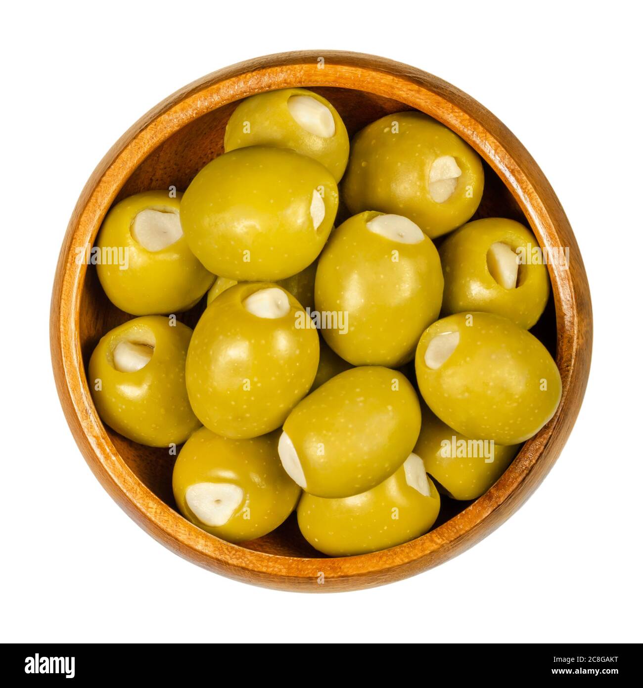 Olive verdi farcite con spicchi d'aglio in una ciotola di legno. Olive grandi, frutta di Olea europaea, farcite a mano con pezzi d'aglio sottaceto. Primo piano. Foto Stock