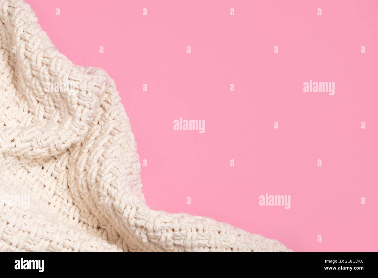 Confortevole coperta o pullover beige lavorato a maglia su sfondo rosa pastello con spazio per la copia Foto Stock