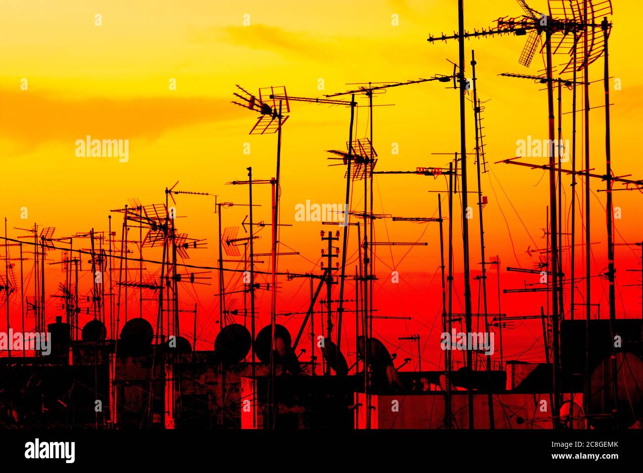 TV, antenne televisive e piatti satellitari sui tetti all'alba. Foto Stock