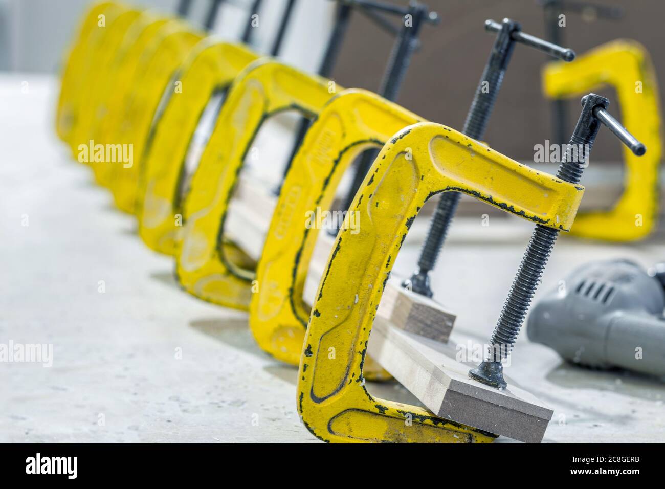 Produzione di mobili in legno in una fabbrica. Incollaggio di pezzi di mobili con morsetti. Foto di alta qualità Foto Stock