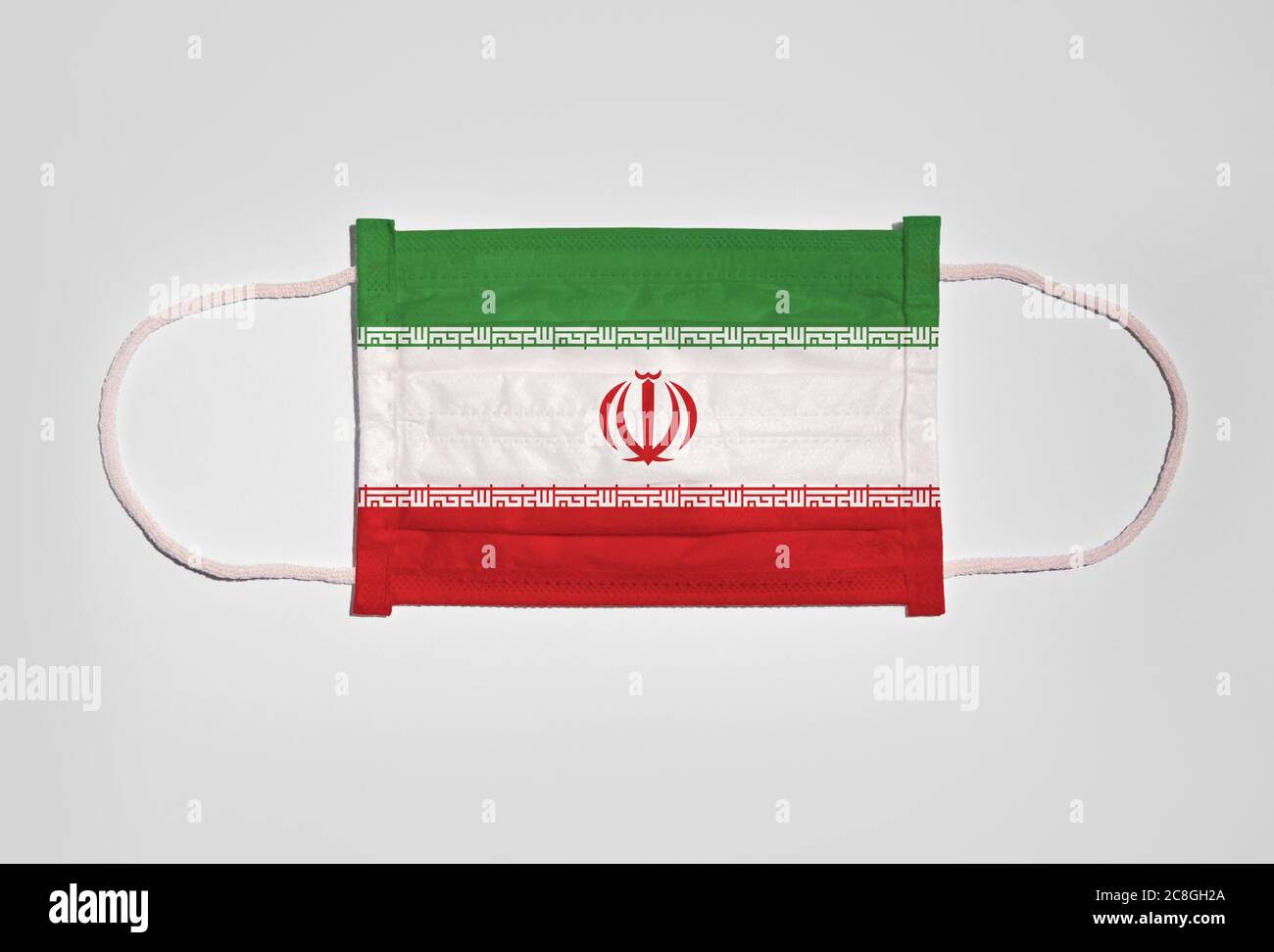 Immagine simbolo crisi corona, protezione della bocca, maschera respiratoria, bocca e protezione del naso con bandiera dell'Iran, sfondo bianco Foto Stock