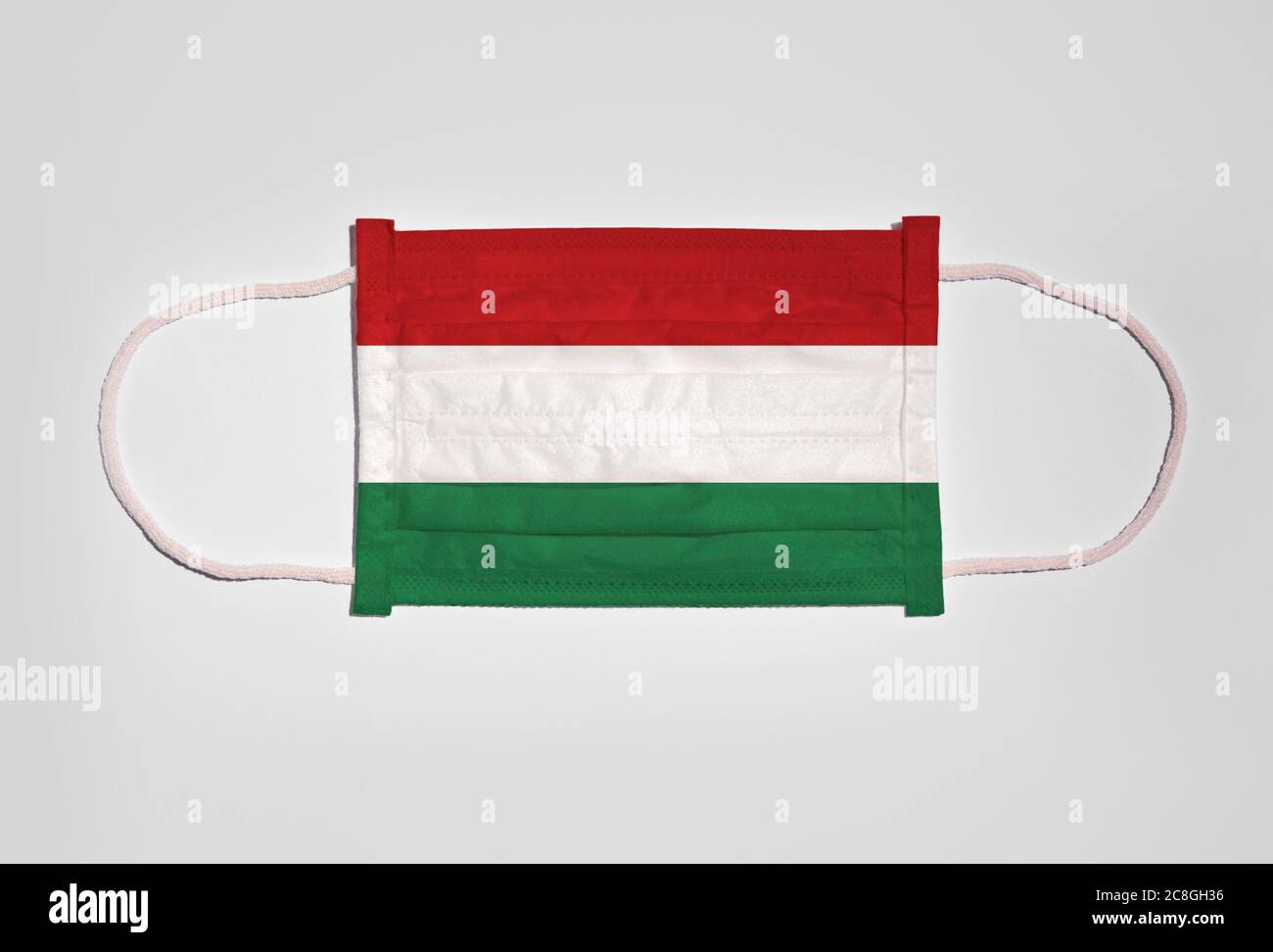 Immagine simbolo crisi corona, protezione della bocca, maschera respiratoria, bocca e protezione del naso con bandiera di Ungheria, sfondo bianco Foto Stock