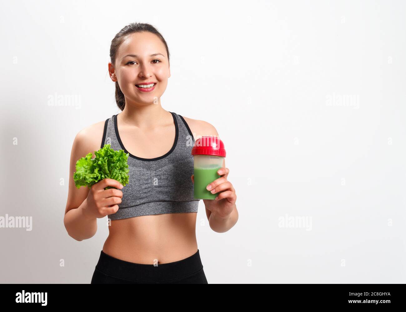 giovane donna fitness con insalata e cocktail dietetico su sfondo bianco isolato Foto Stock
