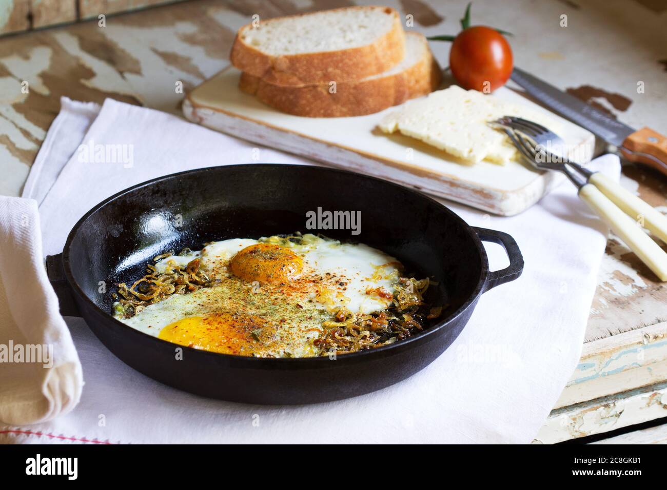 Uova fritte con cipolle e spezie in una padella di ghisa. Foto Stock