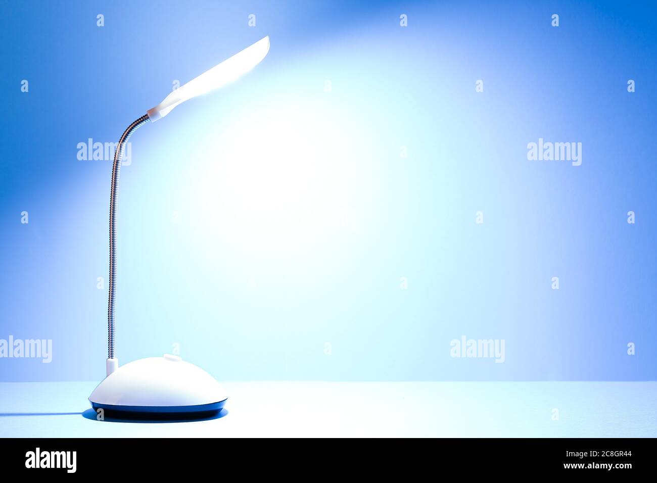 lampada da tavolo illuminata contro la superficie blu chiaro Foto Stock