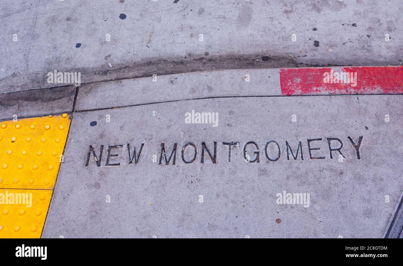 Cartello con il nome di New Montgomery Street stampato su un marciapiede nel centro di San Francisco. Pavimentazione tattile conforme alle norme ADA gialle. Vernice rossa intemperie sul marciapiede. Acceso Foto Stock