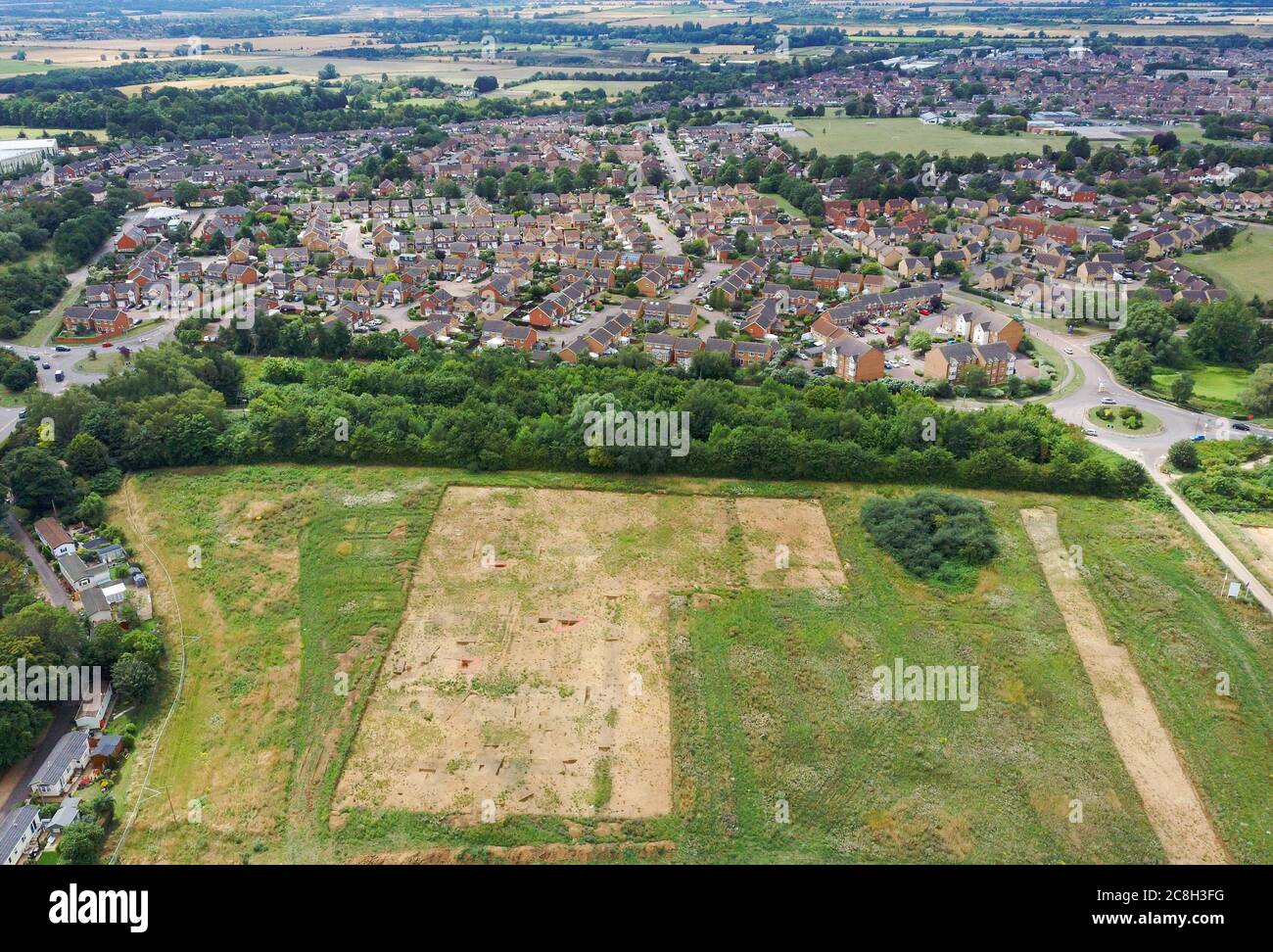 Campo spogliato per uno scavo archeologico con invadente sviluppo di scorte di alloggi moderni. Biggleswade, Bedfordshire, Regno Unito. Foto Stock