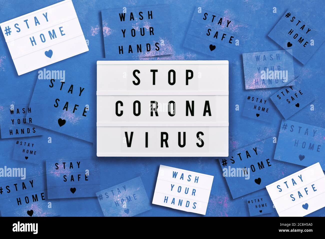 STOP CORONA VIRUS, SOGGIORNO A CASA, STARE AL SICURO e LAVARE LE MANI scritte in scatola luce su sfondo blu. Concetto sanitario e medico. Vista dall'alto. Quarant Foto Stock