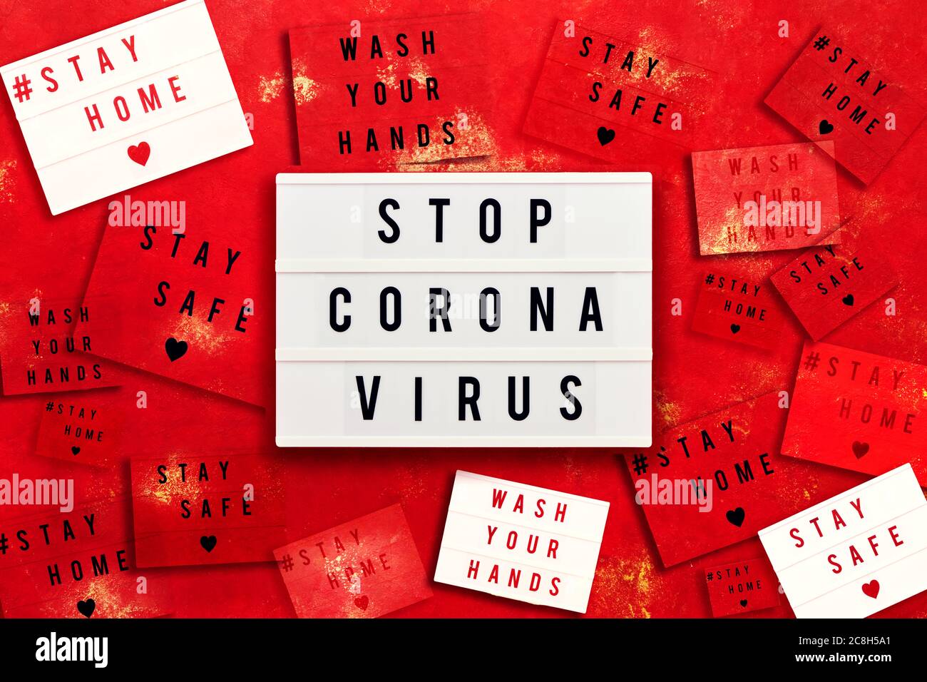 STOP CORONA VIRUS, SOGGIORNO A CASA, STARE AL SICURO e WAHS LE MANI scritte in scatola luce su sfondo rosso. Concetto sanitario e medico. Vista dall'alto. Quaranti Foto Stock
