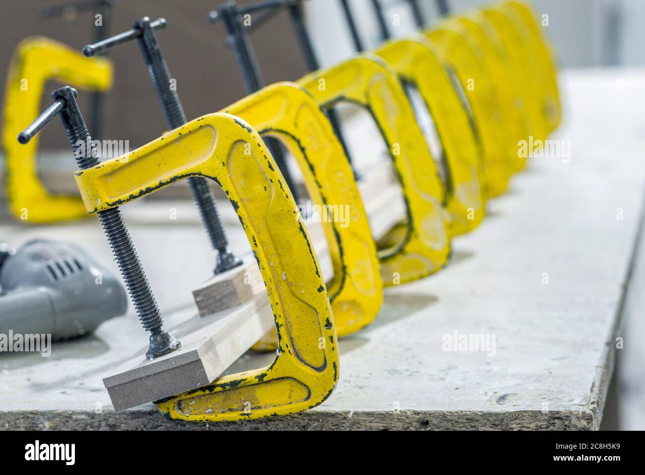 Produzione di mobili in legno in una fabbrica. Incollaggio di pezzi di mobili con morsetti. Foto di alta qualità Foto Stock