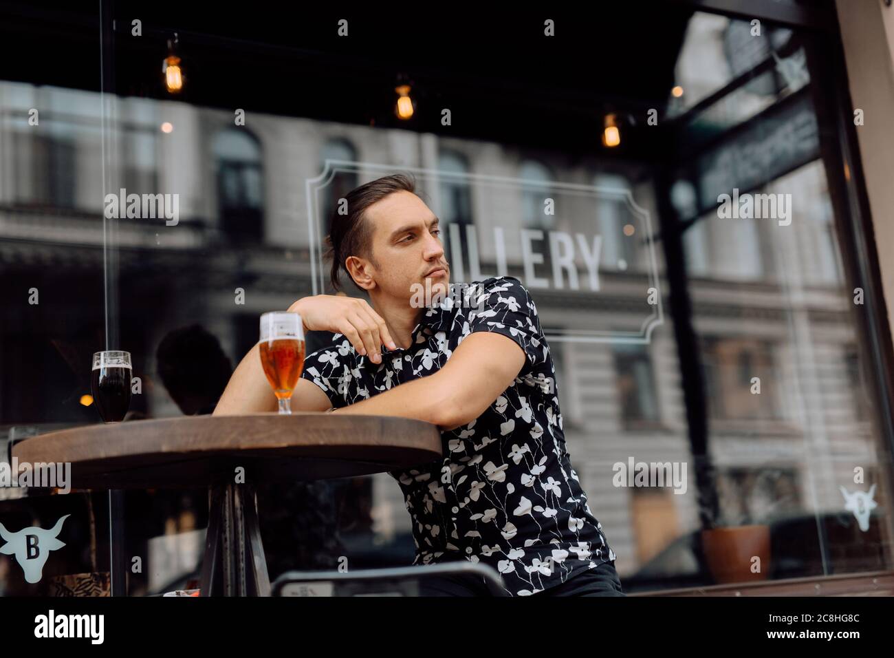 felice attraente uomo che si rilassa e che ha una birra in un pub. Foto Stock