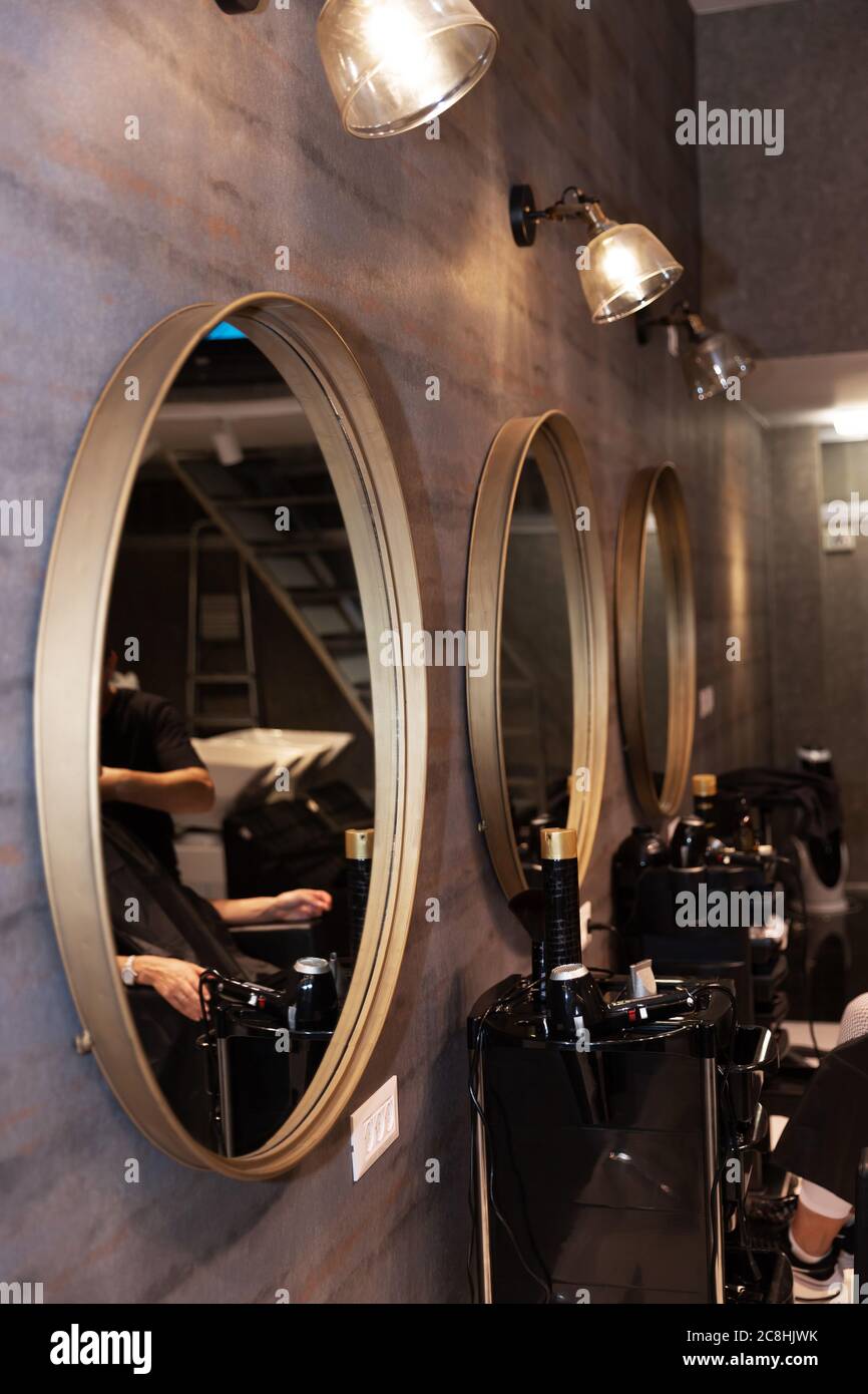 Interno parrucchiere. Una donna si siede in un barbiere, un uomo taglia i  capelli. Moderni specchi e lampade rotonde, un tavolo da parrucchiere con  tutte le attrezzature e Foto stock - Alamy