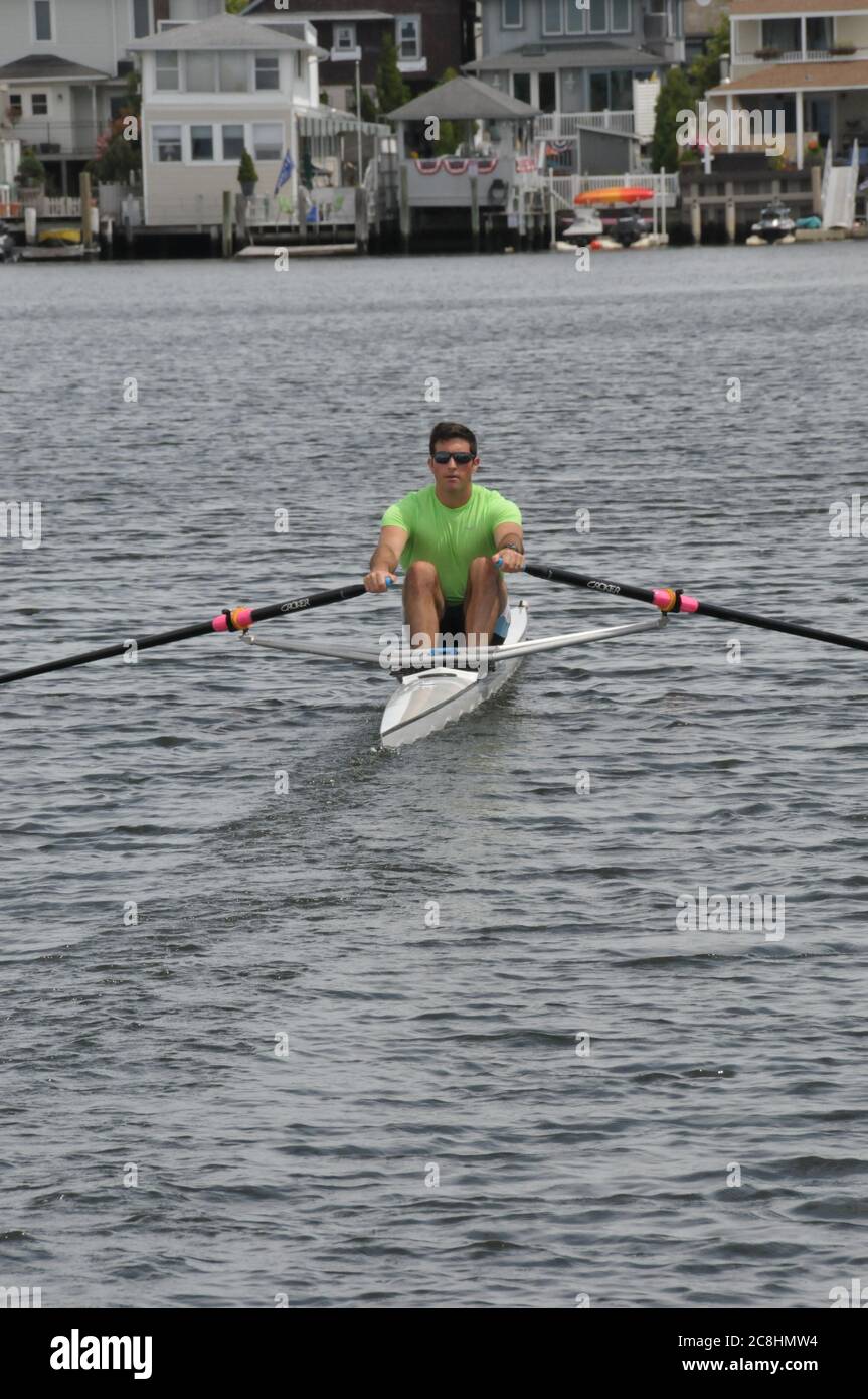 Vogatore e il suo singolo cranio che si dirige verso l'esterno per una fila sulla baia. Foto Stock