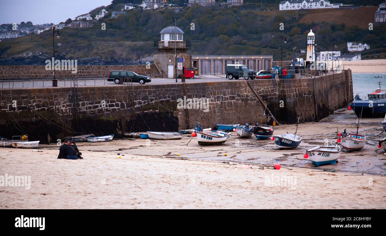 St Ives, UK 03/09/2010: Un panorama al tramonto di una spiaggia all'interno del porto di pescatori di St Ives. L'immagine presenta piccole barche intrecciate sulla sabbia in bassa marea, una coppia Foto Stock
