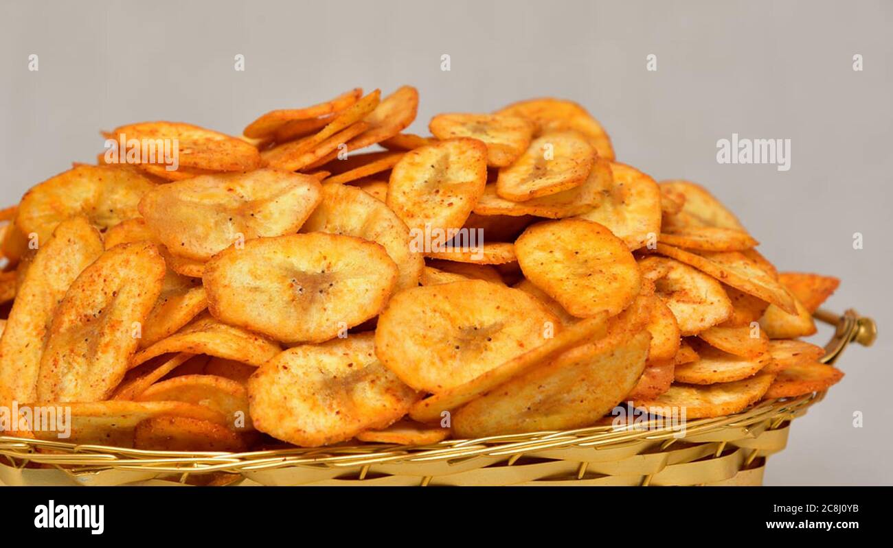 Chip di banana, fette di patate che si trasformano in patatine isolate, fette di kela croccanti, salate, masala (wafer), pomodoro, namkeen, patatine su ciotola dorata. Foto Stock