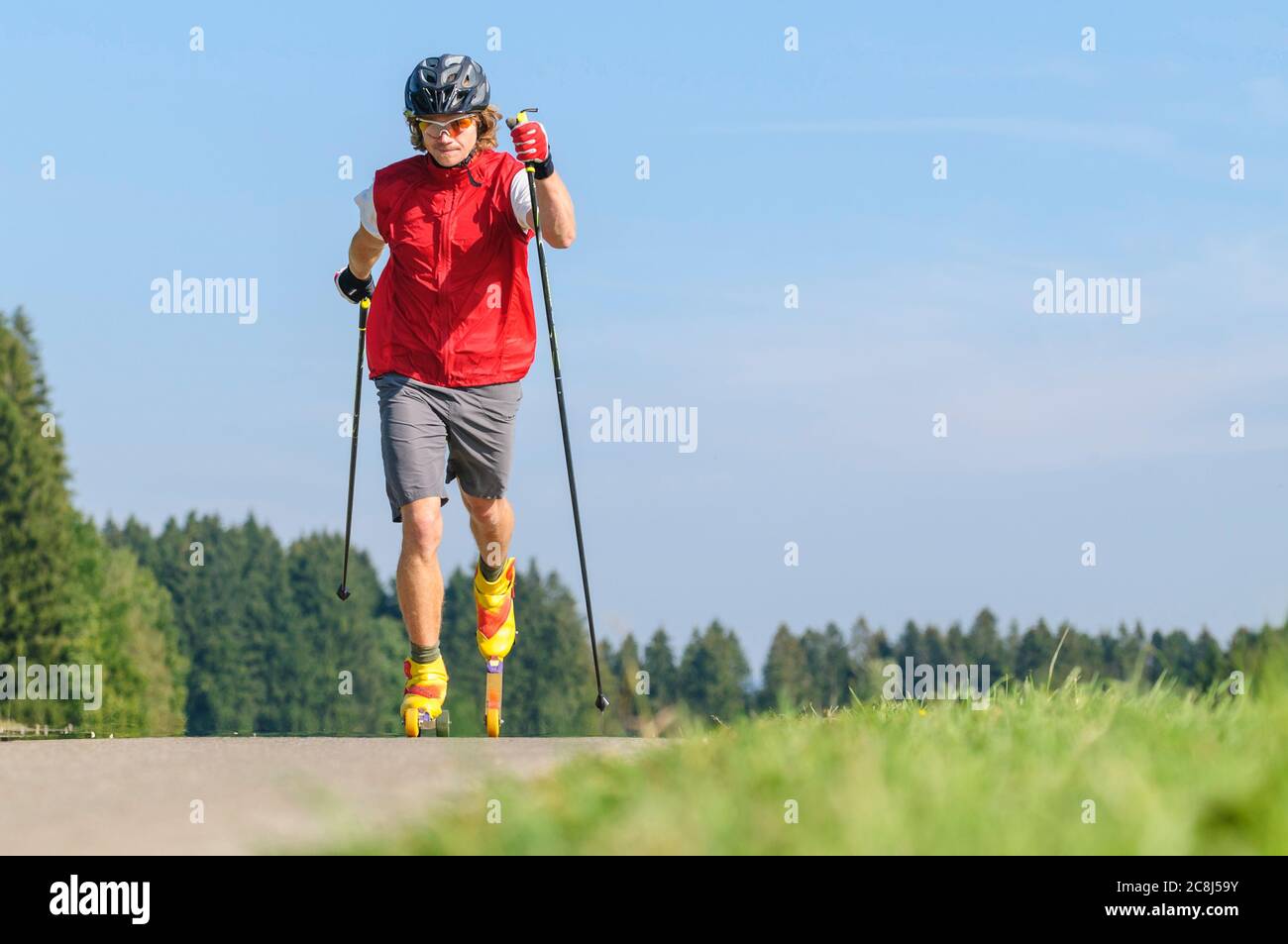 Giovane che fa una sessione di allenamento sui rulli da sci in estate Foto Stock