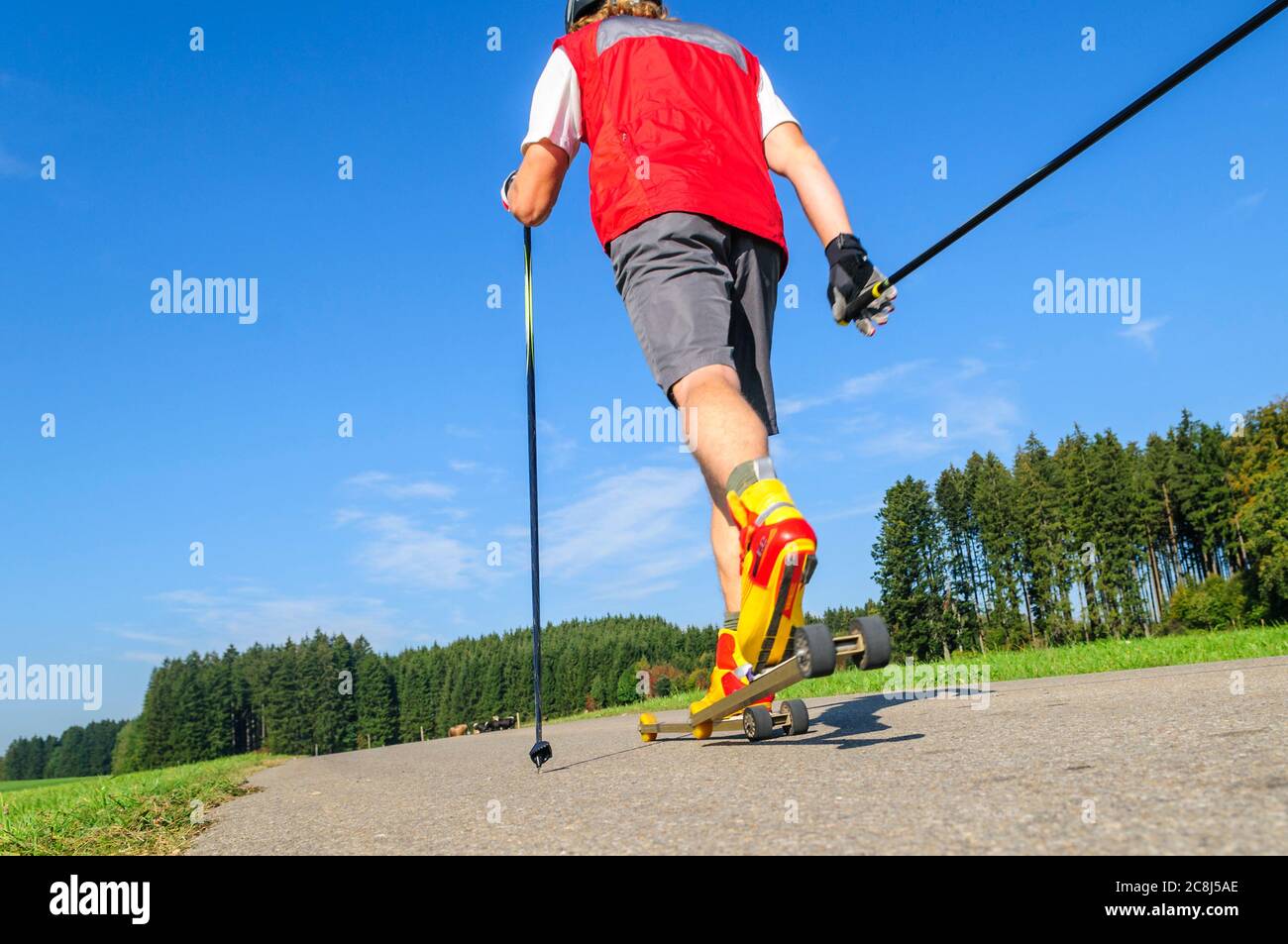 Giovane che fa una sessione di allenamento sui rulli da sci in estate Foto Stock