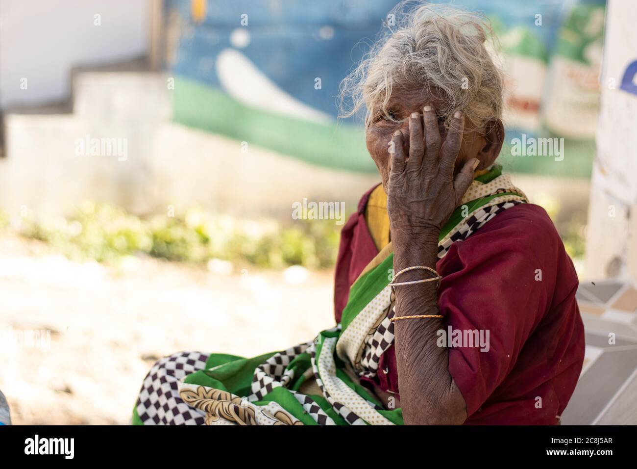 Chennai - Tamilnadu India. 24 luglio 2020. Una vecchia signora seduta con le mani sulla bocca, ritratto donna esterno Foto Stock