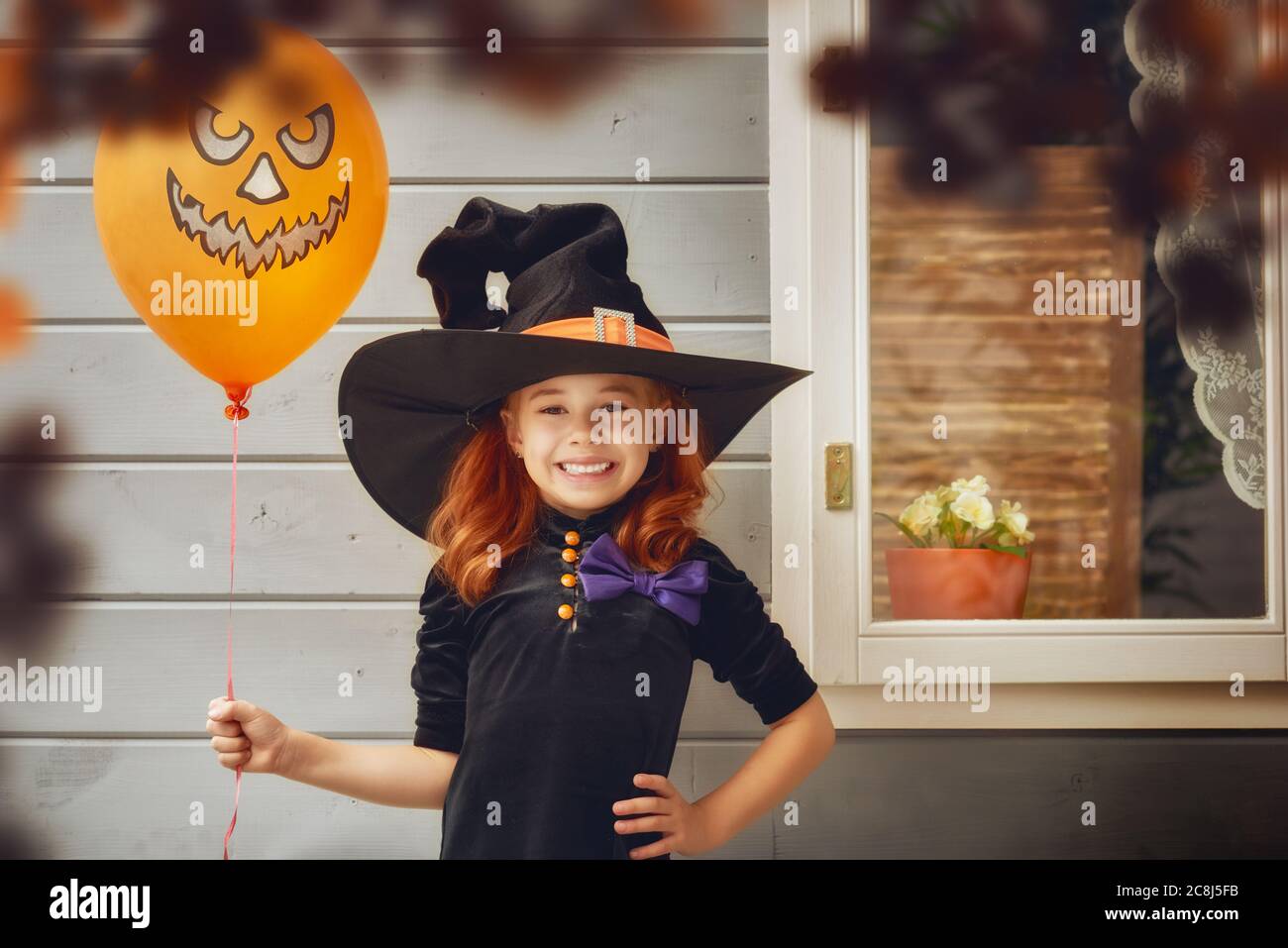 Felice Halloween! Carino allegro piccolo strega all'aperto. Bella ragazza bambino in costume strega vicino casa decorata a Halloween. Foto Stock