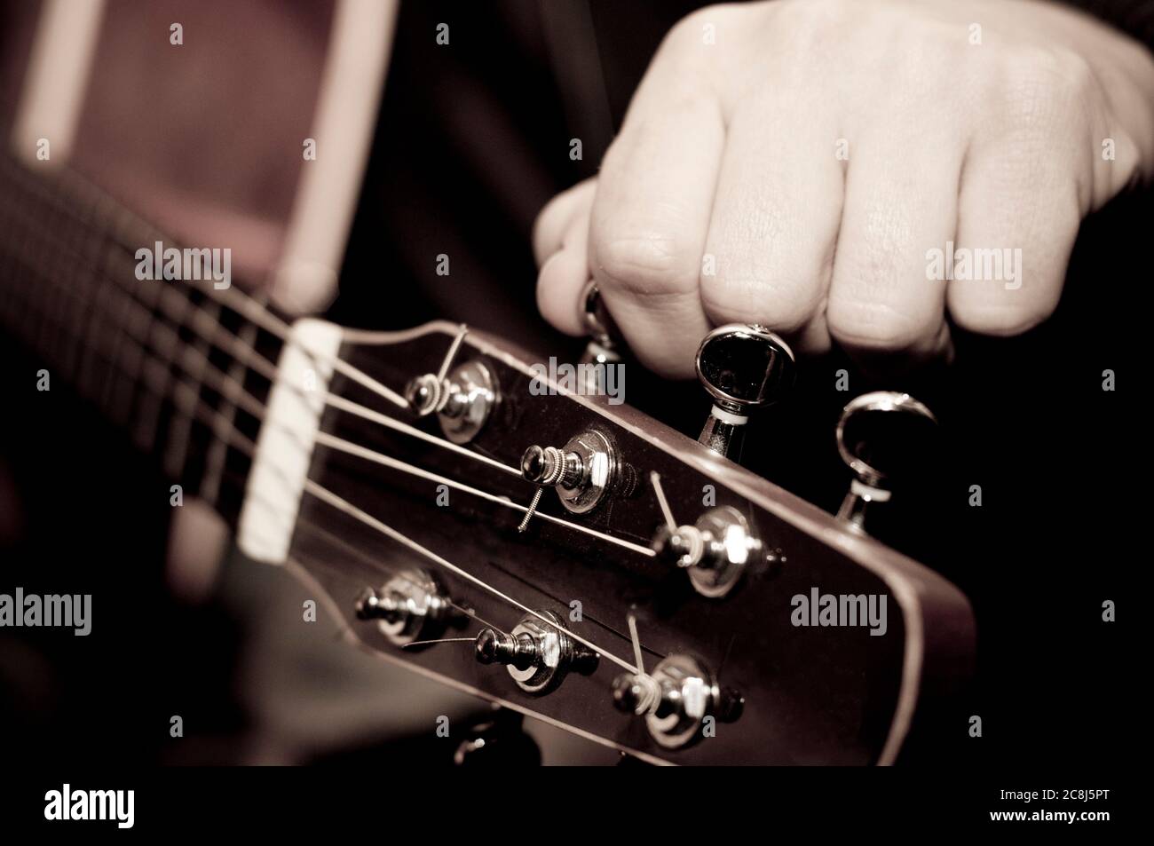 Chitarrista acustico che sintonizza il suo strumento Foto Stock