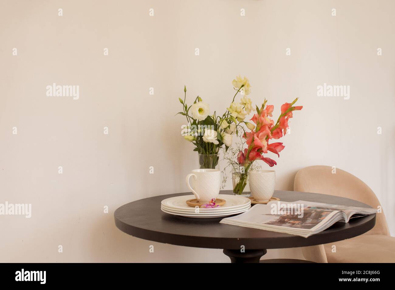 Fiori e riviste vicino a stoviglie sul tavolo Foto Stock