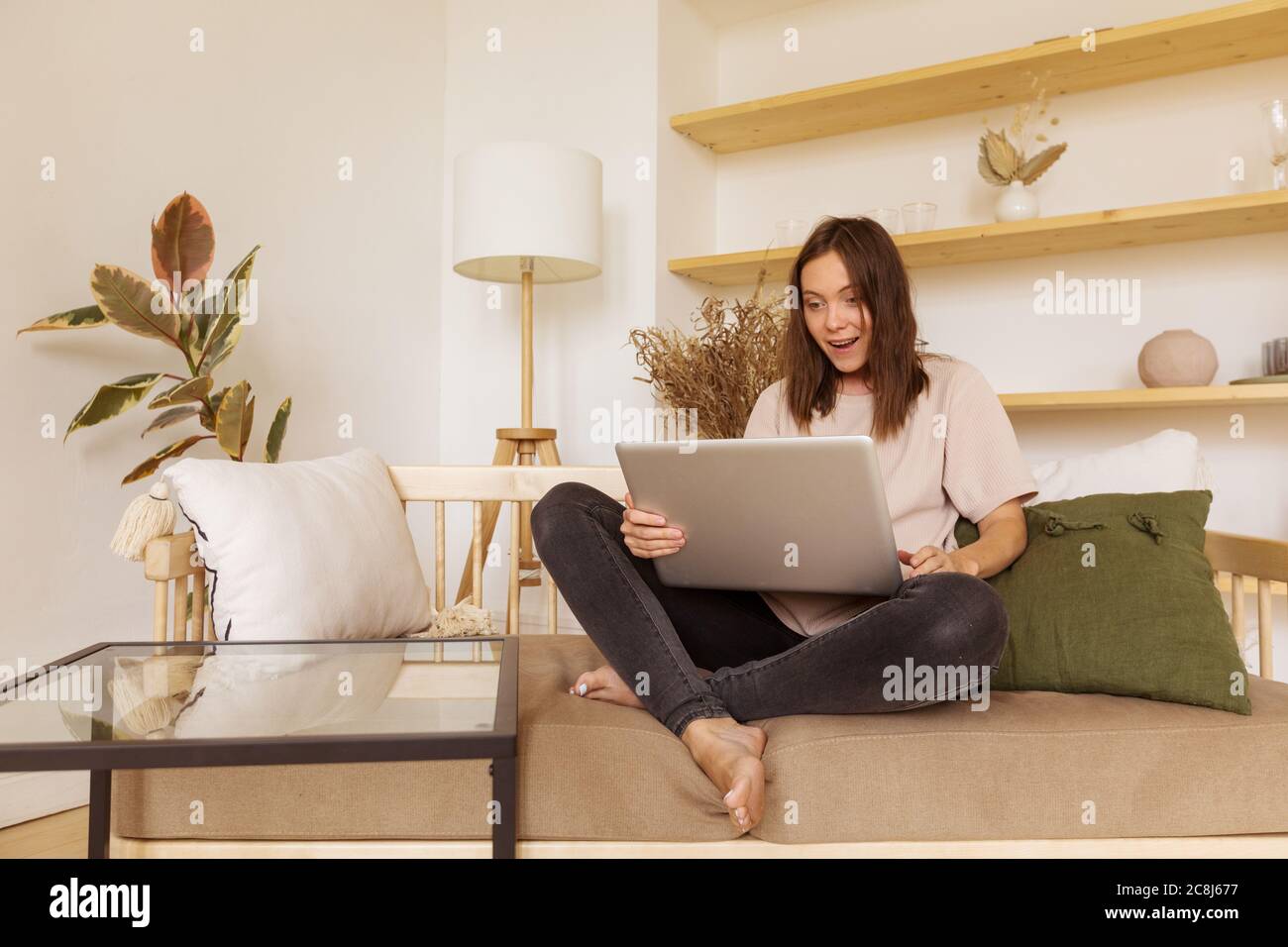 Donna entusiasta che usa il laptop sul divano Foto Stock