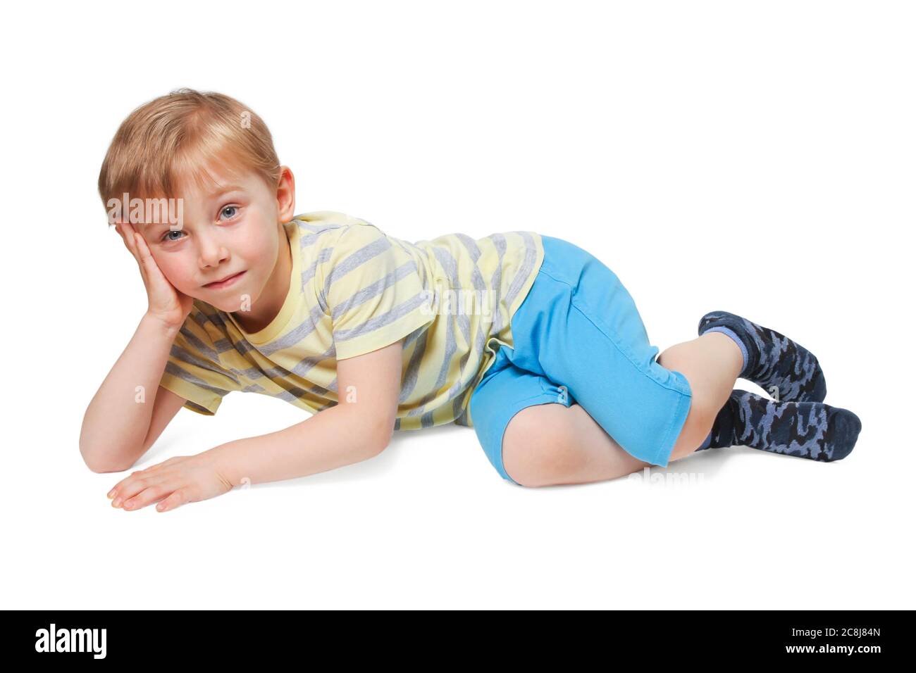 Il ragazzo in pantaloncini blu e una t-shirt a righe gialle che si posano mentre si stendono in giù isolato su bianco Foto Stock