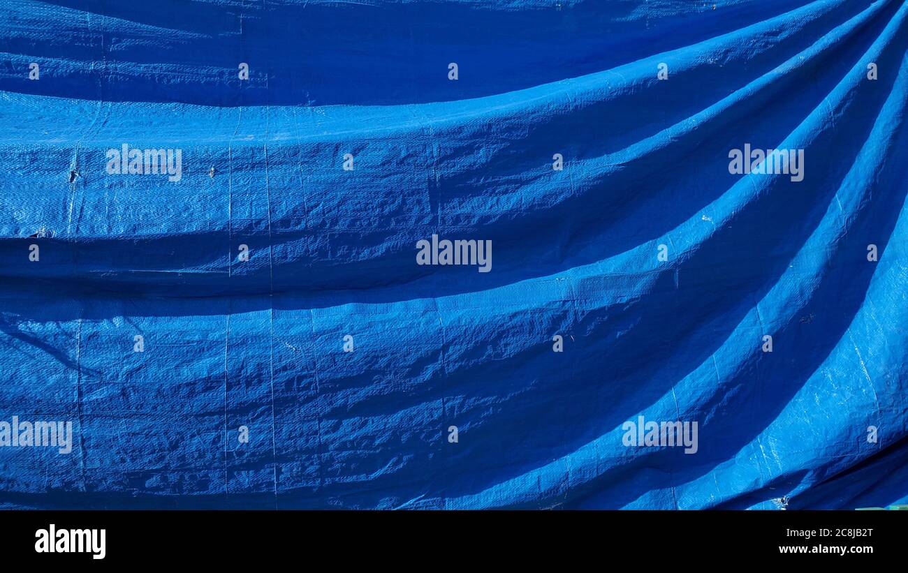 Pieghe di tessuto di plastica rumpled con spazio di copia. Vecchio sfondo blu drappeggi con diagonale struttura ondulata Foto Stock