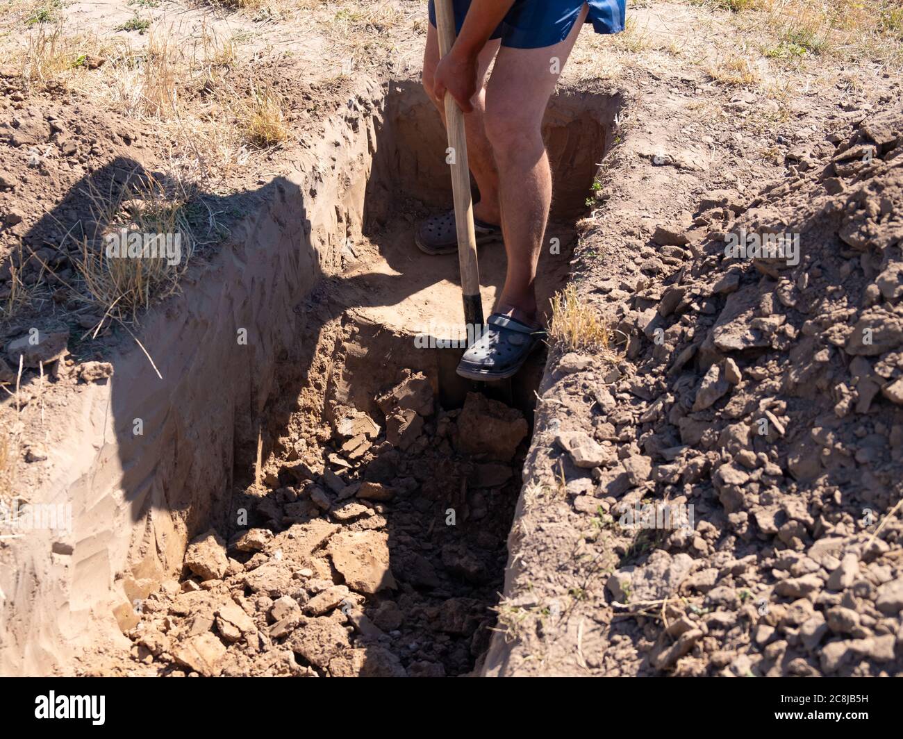 il gravedigger scava una tomba. un uomo scava un buco con una pala in un cimitero. Foto Stock