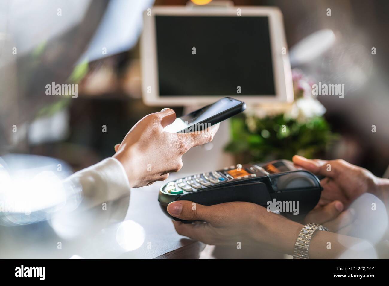 Closeup uomo asiatico mano di cliente che paga soldi via canale contactless da mobile banking applicazione a piccolo imprenditore al tavolo in negozio di caffè, Smal Foto Stock