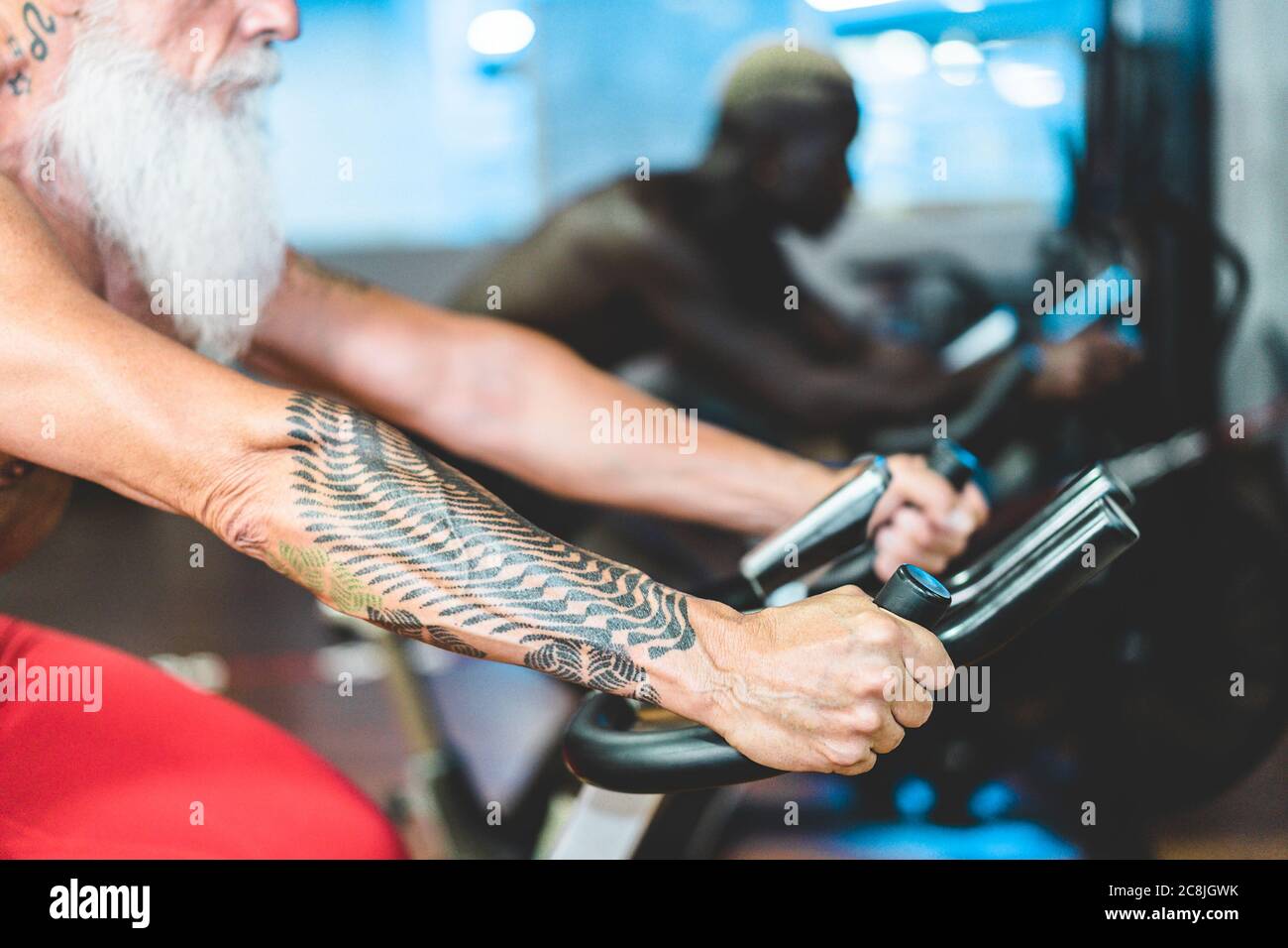 Persone di diverse generazioni ed etnie che fanno sessione di allenamento su cardio-cyclette all'interno del club palestra - Fitness, filatura, stile di vita sano e s. Foto Stock