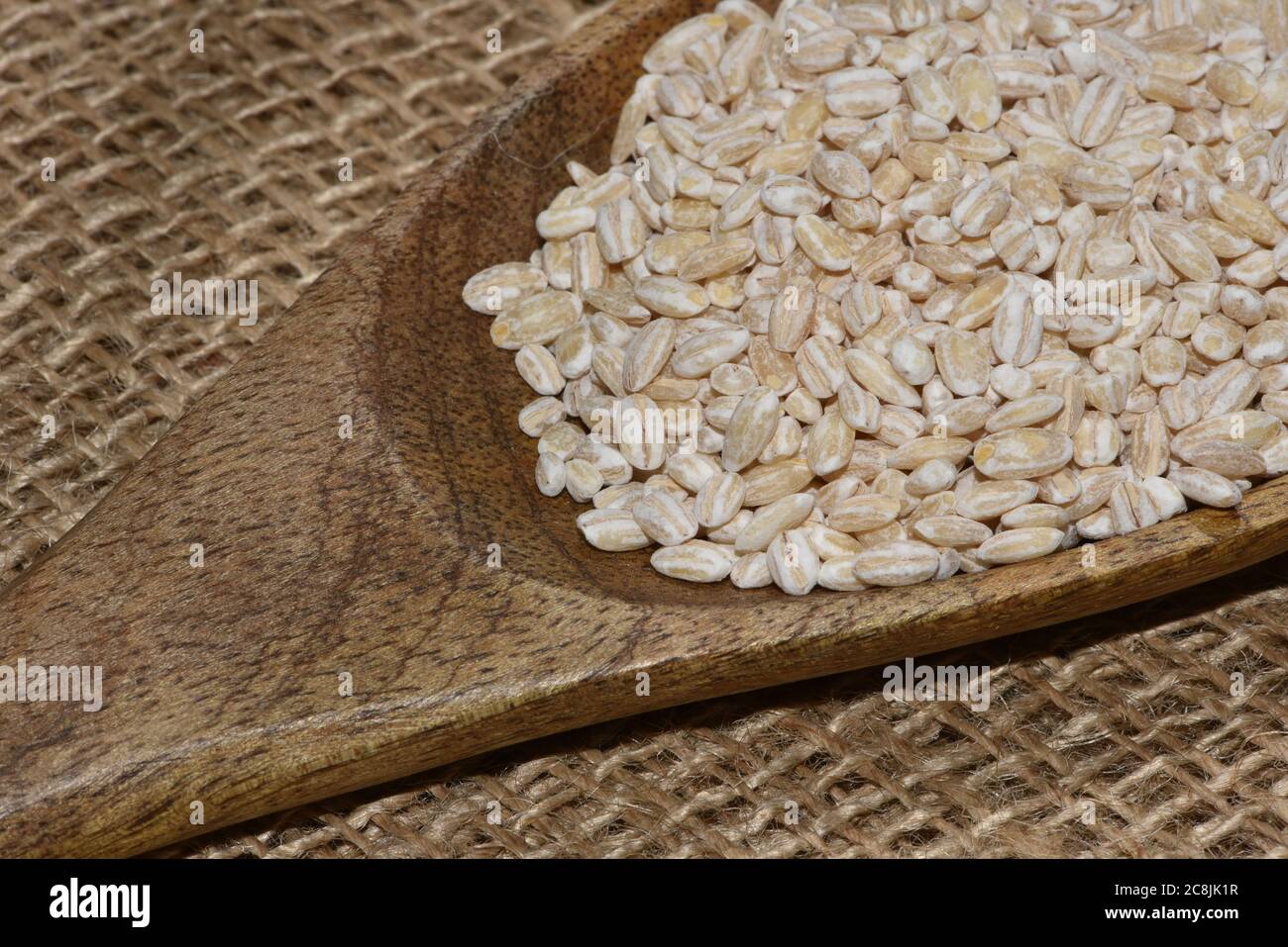 orzo perlato con cucchiaio di legno vicino superficie vista dall'alto sfondo, orzo perlato Foto Stock