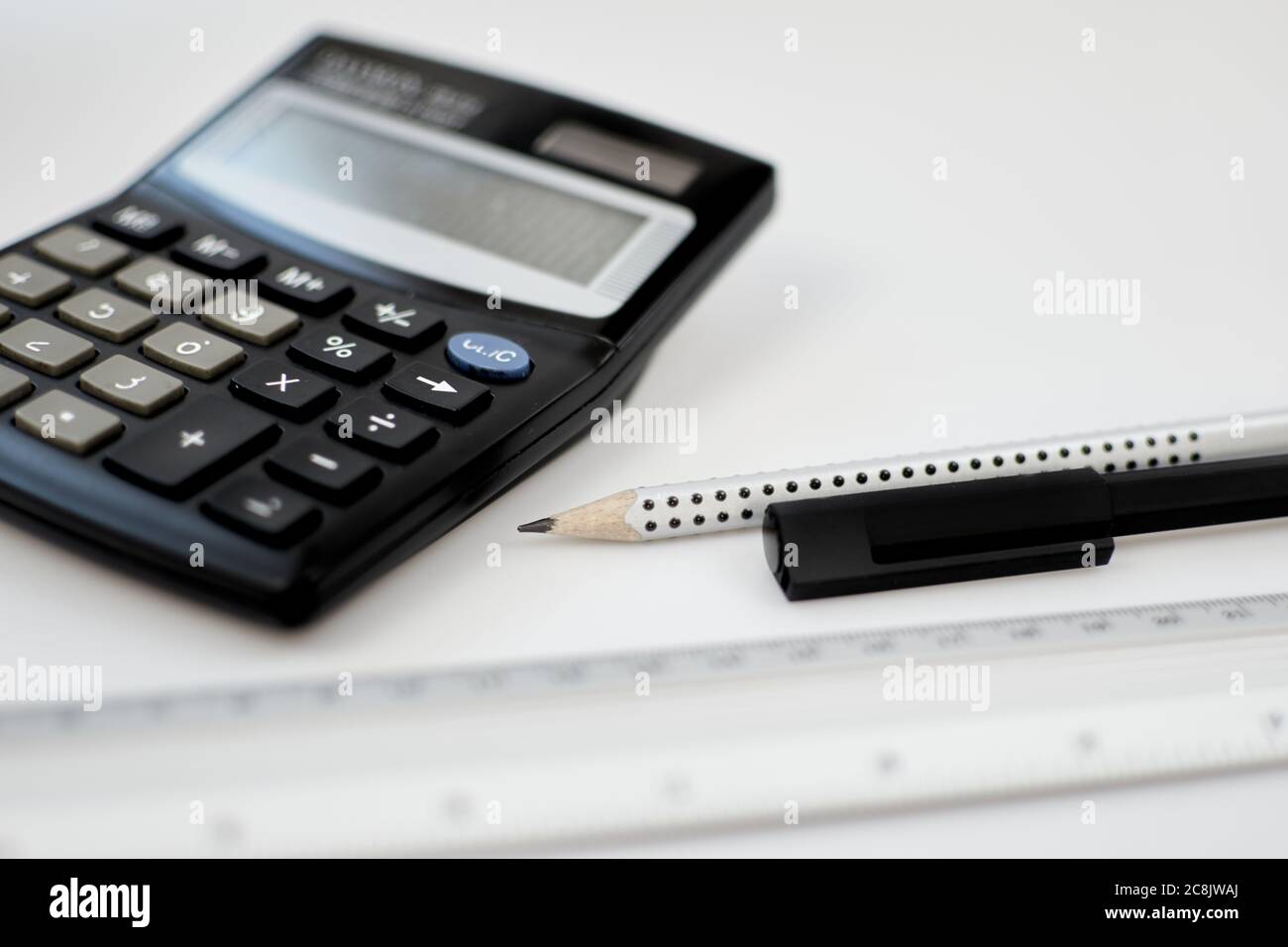Primo piano calcolatrice contabile tavolo da scrivania bianco per ufficio vicino a penna, matita, bilancia di misurazione e altri materiali di consumo per ufficio Foto Stock