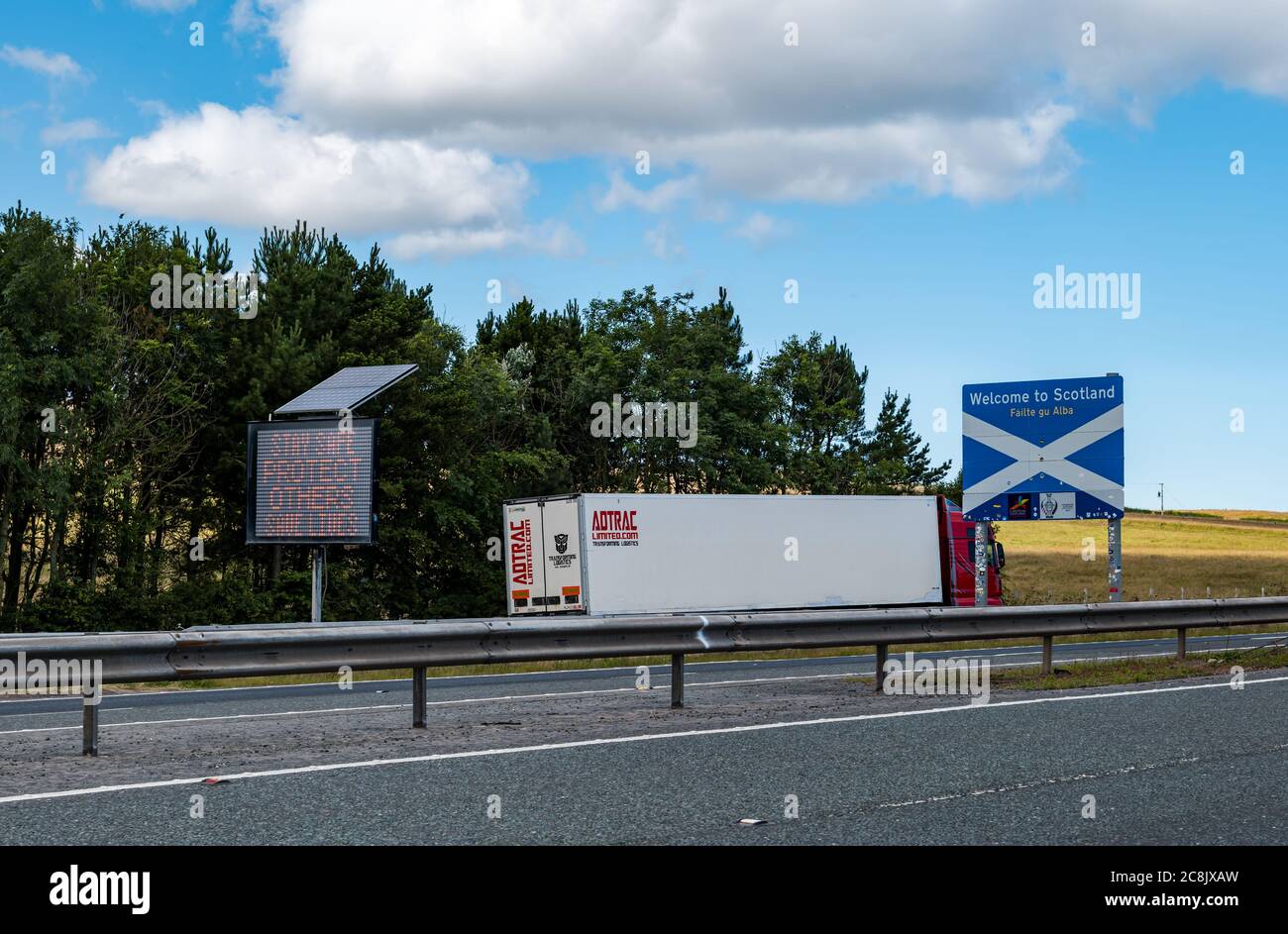 Benvenuto in Scozia segno e governo slogan pandemic rimanere sicuro, proteggere gli altri & salvare vite sulla A1 a doppia carreggiata, confine inglese scozzese, Regno Unito Foto Stock